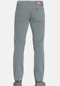 Zadní pohled na šedé džíny rovného střihu se šitými zadními kapsami a hnědou nášivkou Carrera na pasu.