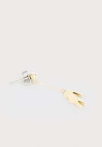 Gold-tone earring with a sculptural design featuring a winged attachment and a silver-tone stud. Textured chain links connect elements.
