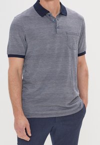 Polo rayé en bleu marine et bleu clair, présentant un col et trois boutons, des manches courtes et un motif de tissu texturé.