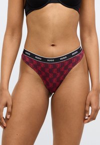 Bas de bikini rouge avec motif logo "HUGO", ceinture élastique noire, design taille basse et texture de tissu doux.