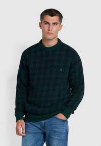 Groene en marineblauwe gebreide trui met een ronde hals en geribbelde manchetten, voorzien van een subtiel geometrisch patroon en een klein goud geborduurd logo.