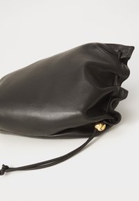 Čierna kožená kabelka so zaobleným tvarom, so sťahovacou šnúrkou a zlatým kovovým detailom. Hladká textúra, minimalistický dizajn.
