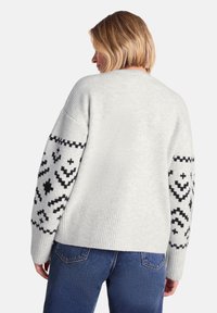 Light gray knitted sweater featuring long sleeves with black patterned accents. Ribbed texture on body and cuffs.