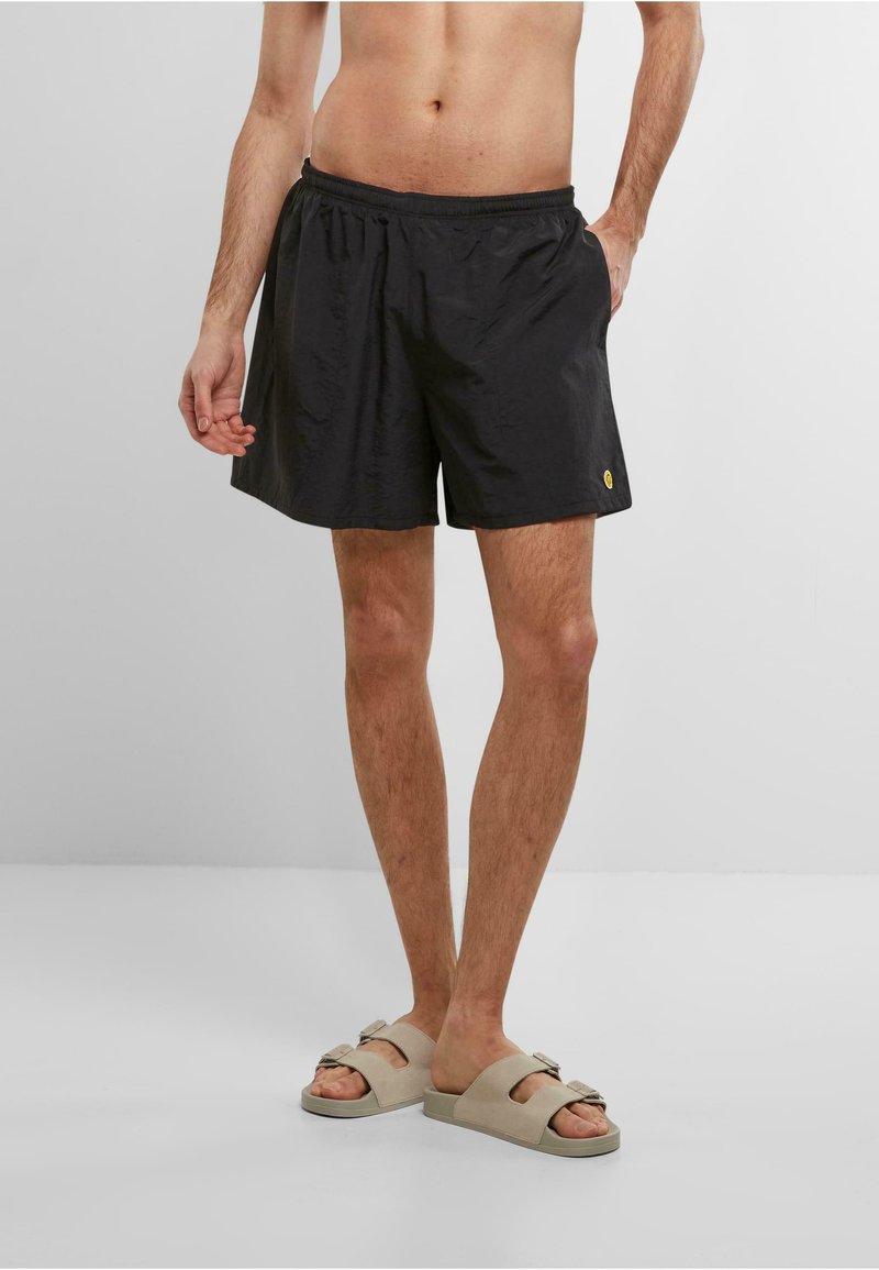 Sorte svøm shorts med elastisk talje, sidelommer og et lille gult logo. Letvægts, glat tekstur med en afslappet pasform.