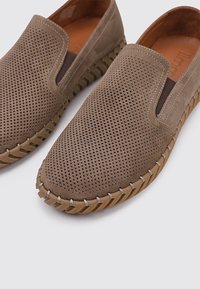 Zapatos marrones de slip-on perforados con un acabado suave de ante, paneles laterales elásticos y una suela de goma contrastante con detalles trenzados.