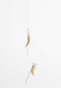 Orecchini a goccia con un design a corno curvo in crema sospeso da una catena d'argento con un gancio a cerchio in argento. Estetica minimalista e moderna.