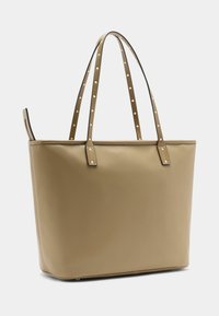 Bézs bőrből készült nagy kézitáska sima felülettel, téglalap alakú, stílusos fogantyúin díszítő szegecsekkel. Nyitott tetejű, minimalista kialakítású.