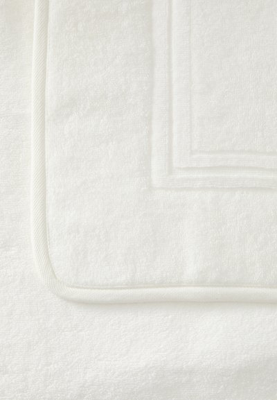 Σωρός από λευκές πετσέτες από περκάλι, με πλούσια υφή και καθαρές άκρες. Μία πετσέτα έχει λείο, περιμετρικό τελείωμα που αναδεικνύει την ποιότητά της.