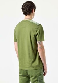 Grøn T-shirt med korte ærmer og rund hals; har et kontrasterende struktureret skulderpanel; glat, let figursyet bomuldsstof.