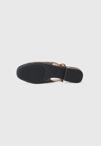 Brun, teksturert såle av sandaler med gummibunn og et hevet grep mønster. Har en buet form med minimale brudd detaljer.