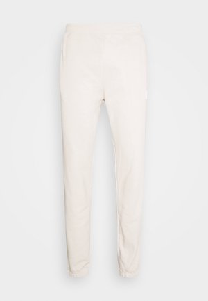 Pantalon de jogging slim couleur crème avec ceinture élastique et poignets élastiques, présenté sur un fond uni.