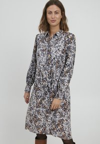 Rochie florală cu guler, mâneci lungi și talie strânsă. Prezintă un model în culori negre, albe și cărămizii. Fabricată dintr-un material ușor.