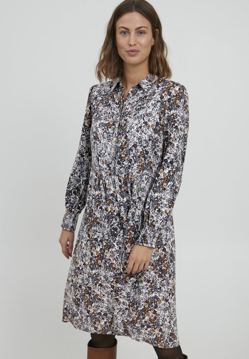 Rochie florală cu guler, mâneci lungi și talie strânsă. Prezintă un model în culori negre, albe și cărămizii. Fabricată dintr-un material ușor.