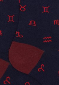 Calze navy con simboli zodiacali rossi su tutta la superficie, con punta e tallone rossi a tinta unita per contrasto e texture aggiuntiva.