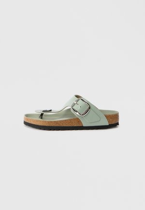 Sandales vert clair avec une semelle en liège, conçues avec un entre-doigts et une large sangle comportant une boucle en argent pour l'ajustement.