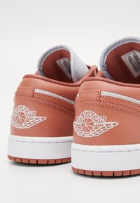 Paired de baskets Air Jordan couleur rouille vues de dos, avec des semelles intermédiaires blanches et le logo ailes brodé.