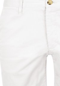 White cotton trousers featuring a smooth texture, slim fit design, a single golden button at the waist, and minimalistic stitching details.
