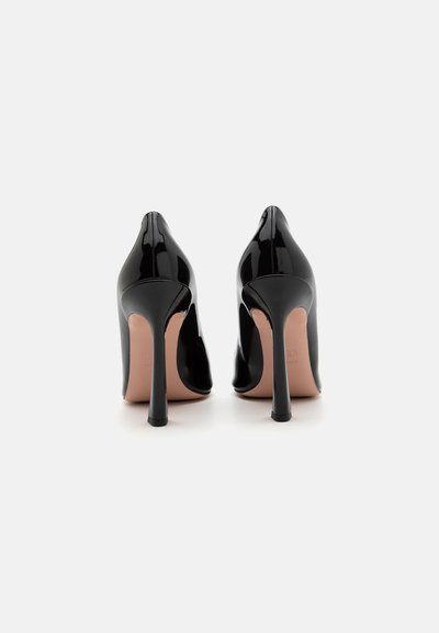 Pantofi cu toc înalt din piele lacuită neagră, cu vârful ascuțit și tocuri subțiri de tip stiletto. Textură netedă cu branț nud.