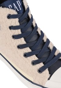 Beige syntetické tenisky se strukturovaným designem, texturovaným, huňatým svrškem, námořnickými šněrovadly a akcenty, gumovou podrážkou.