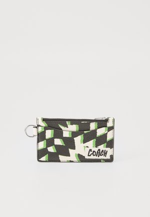 Porte-cartes en cuir texturé avec un motif géométrique noir, blanc et vert ; il dispose d'un compartiment zippé et d'un anneau pour clé.