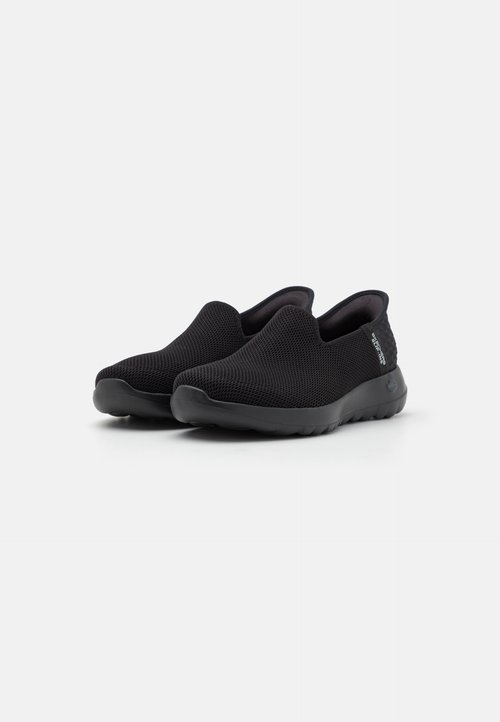 Μαύρα παπούτσια slip-on με υφασμάτινο άνω μέρος και ευέλικτη ελαστική σόλα, που διαθέτουν μινιμαλιστική σήμανση στο πλάι.