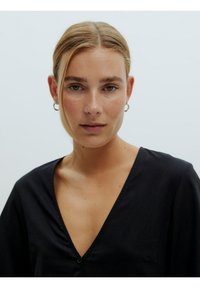 Zwarte v-hals shirt met een knoopdetail, gemaakt van lichte stof. Heeft een losse pasvorm en lange mouwen. Glad textuur.