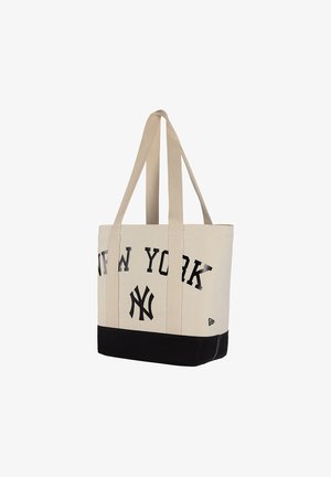 Sac fourre-tout beige et noir avec longues poignées, texte "NEW YORK" et logo des New York Yankees sur le devant.