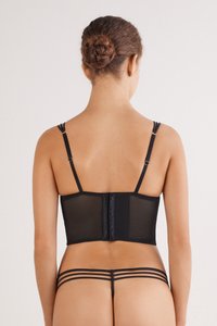 Conjunto de lencería de malla negra que incluye un corsé estructurado con tirantes ajustables y un cierre de enganche, acompañado de un tanga minimalista.