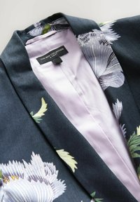 Floralni kimono kaput koji sadrži tamnoplavu tkaninu sa velikim svijetloplavim i zelenim cvjetnim uzorcima; meka ljubičasta podstava. Oznaka vidljiva unutra.