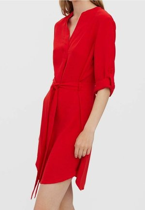 Czerwona sukienka do kolan z dekoltem w serek, paskiem w talii i rękawami o długości do łokcia. Wykonana z teksturowanej tkaniny o gładkim wykończeniu.