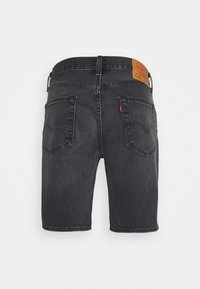 Shorts en denim noir avec deux poches arrière, passerelles pour ceinture, et un patch en cuir marron de la marque Levi's sur la ceinture.