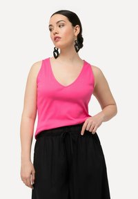 Top fucsia senza maniche con scollatura a V abbinato a pantaloni neri con coulisse. Tessuto morbido con vestibilità comoda. Orecchini con accento audace completano il look.