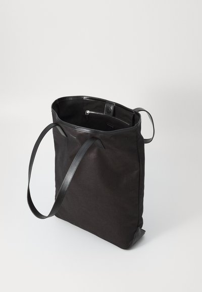 Musthave must käekott on valmistatud kanvasest ja nahakate, millel on avar sisemus ja pikad nahkrihmad kandmiseks. Sisu on varustatud lukuga taskuga.