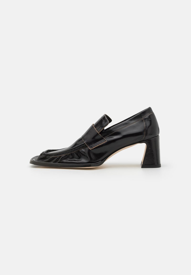 Black leather pump with a rounded toe, ruffled detailing at the front, and a medium block heel featuring a textured finish.