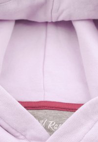 Ljuslila sweatshirt med en mjuk textur, med röd kant vid halsen och en grå innertagg med vit text.