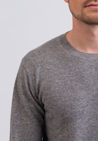 Maglione in maglia grigio chiaro con scollo rotondo e polsini a coste. Tessuto morbido con leggere variazioni di colore. Vestibilità moderna che copre la parte superiore del corpo.