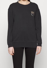 Felpa nera in cotone con maniche lunghe, scollatura rotonda e un piccolo logo sul petto. Presenta polsini e orlo a costine.