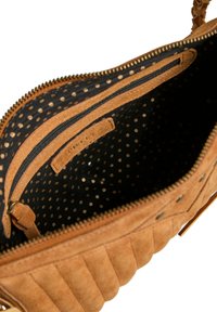 Sac à main en daim tan avec des rayures texturées, fermeture zippée et doublure à pois noire et or. Comprend une poche zippée intérieure.