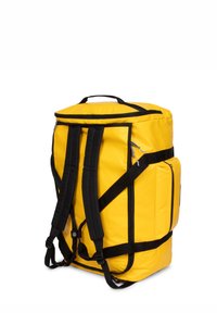 Mochila de nylon amarilla con correas y detalles negros. Cuenta con un asa en la parte superior, compartimentos con cremallera y correas de hombro ajustables y acolchadas.