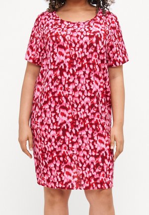 Frau trägt ein kurzärmeliges, knielanges Kleid mit einem rosa-rot abstrakten Tierdruckmuster.