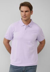 Lichtpaarse polo met een klassieke kraag, korte mouwen en een subtiele logo op de borst. Gemaakt van een gladde, gestructureerde stof.