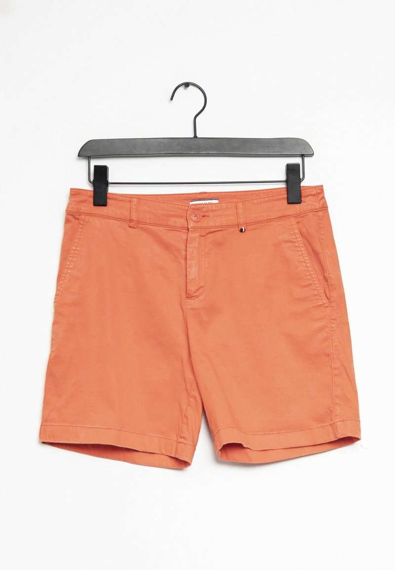 Short en coton orange avec poches avant et fermeture par boutons, suspendu à un cintre en plastique noir sur fond blanc.