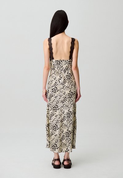 Vestido con estampado de leopardo en crema y negro, con tirantes adornados con encaje, silueta ajustada y dobladillo a media pierna con aberturas laterales.