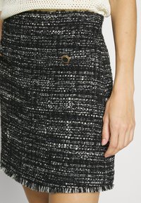 Mustat ja valkoiset tweed-hameet, joissa on teksturoitu kangas, fringehaitari ja kullansävyiset metalliosat, sekä tiukka siluetti.