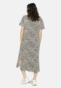 Maxikleid mit Leopardenmuster und kurzen Ärmeln, mit seitlichen Schlitzen. Hergestellt aus leichtem Stoff, in einer Farbkombination aus Creme, Braun und Schwarz.