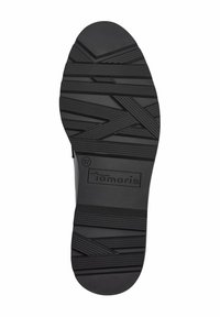 Semelle d'une chaussure noire avec des rainures diagonales texturées et le nom de la marque "Tamaris" embossé près du talon, taille 37.