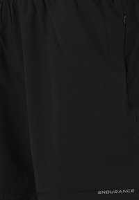 Schwarze Sportshorts aus leichtem Stoff, mit einer glatten Textur, elastischem Bund und einer seitlichen Reißverschlusstasche. "ENDURANCE"-Logo sichtbar.