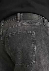 Jeans din denim gri închis, cu un buzunar posterior, cusături în contrast și o etichetă din piele pe talie cu text embossat.
