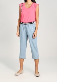 Lyserød ærmeløs top med V-hals, parret med lyseblå cropped bukser. Behagelige beige flade sko fuldender outfittet.