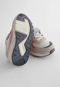 Sneakers w jasnoszarym i różowym schemacie kolorystycznym, wykonane z tekstyliów i zamszu, z teksturowaną gumową podeszwą i wyraźnym wzorem bieżnika.